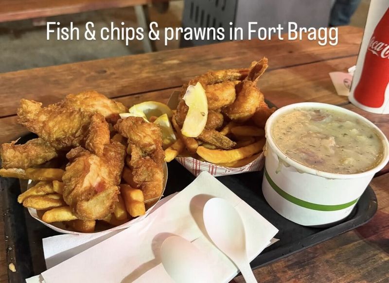 Basket of fried fish and basket of prawns with chips, a cup of chowder, and a Coca-Cola on a tray, text overlay reads Fish and chips and prawns in Fort Bragg
